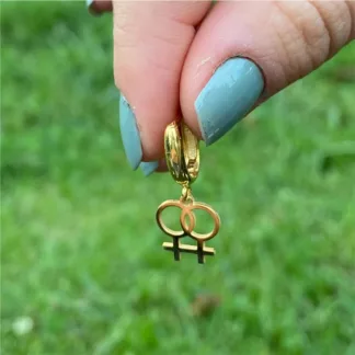 Gold double Venus huggie earring held between fingers